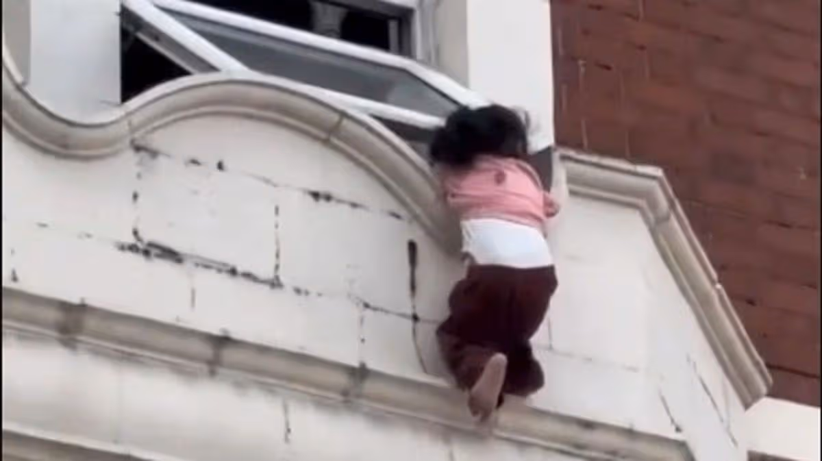 Terrifying moment toddler dangles from ledge in East London as horrified onlookers watch